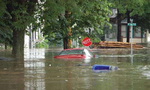 A red sedan is mostly submerged in flood waters in Cedar Rapids, IA. 